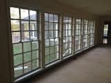 Before: bank of large windows along the back of house that opens into a sunroom/den