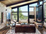 Structural stone walls extend from living spaces to outside buttressed walls, and steel ceiling beams ascend continuously from the Great Room to the uplifted shed roof outdoors. 
