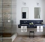 New York City–based designer Jenny Wolf  used mirrors and patterns for this windowless bathroom. Tall mirrored medicine cabinets and a glass shower amplify light from the interior fixtures, brightening up the space. Wolf used built-in cabinets to save floor space. A herringbone wood floor gives the illusion of a larger and warmer bath.  Photo 11 of 11 in These 10 Designers Are Experts at Creating Colorful Bathrooms That Pop