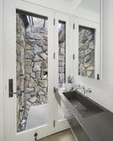 Bath Room, Concrete Counter, Medium Hardwood Floor, Concrete Floor, Wall Mount Sink, Open Shower, and Stone Slab Wall A stone wrapped outdoor shower in the second bath.  Photo 8 of 12 in The Lighthouse by Sarah Lueck