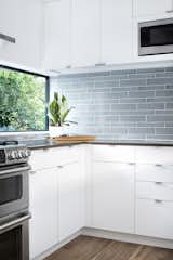 A large horizontal windows in the kitchen washes natural light across the blue accent tiles.

www.clarkrichardson.com