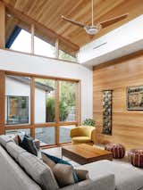 Oblique View of Living Room with Garden Courtyard in the Background: Tall slanting Ceiling makes the Space Lofty and Bright. Rich Materials Bring Warmed and Visual Interest.