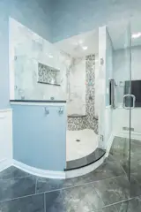 A curved glass door shower opening is a stunning design element in this master bathroom.