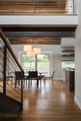 Dining Room, Medium Hardwood Floor, Table, Chair, and Pendant Lighting The introduction of a large dormer to the center of the structure was a simple move, but provides circulation space with the rustic steel stair and bridge  Photo 3 of 9 in Modern Barn by HMHAI