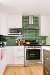 In this kitchen with white cabinets, Fireclay Tile in a classic subway pattern go beyond the standard 18" high backsplash, which brings the eye up the walls of the kitchen. The gloss of the tiles allows light to reflect throughout the space, keeping it bright and cheery despite the darker color.