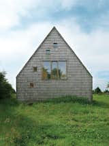 At this wooden A-frame retreat in the Normandy region of France, architect Jean-Baptist Barache designed a home that's both casual and elegant, low-key and surprising. A large central window on one of the end gables of the house is accompanied by a scattering of smaller, square "peek-a-boo" windows. The two windows on the third floor bring light and views into the bedroom, and the window on the first floor fits perfectly into the camouflaged rear door.
