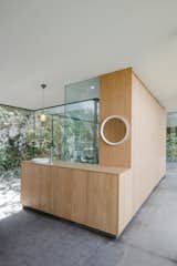 Living Room, Concrete Floor, Pendant Lighting, and Bar Bookmatched wood veneer cabinetry brings a warm, tactile feel to the interiors.  Photos from A Portuguese Glass House Uses Surrounding Foliage as a Privacy Screen