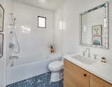 One of the bathrooms on the second floor contrasts crisp white tile on the walls with geometric blue tile on the floor.