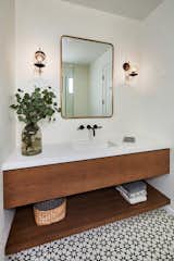 A white and wood bathroom is complemented by patterned geometric tile and a simple metal mirror.