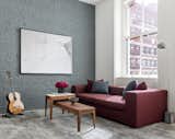 The burgundy sofa mirrors the brick facade outside, providing a moment of color against the otherwise neutral colors.