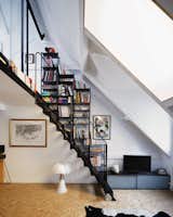 A black steel staircase with integrated storage leads up to a lofted bedroom