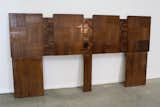 Consisting of dozens of cuts of walnut pieced together like a patchwork quilt, this chunky headboard was designed by American furniture designer Paul R. Evans, who was inspired by the brutalist, hulking concrete structures of the 1970s. The four large panels feature smooth, regular grids of walnut tiles, while the intermediate sections are more irregular and blocky, providing contrasting texture.