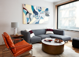 At an apartment in Brooklyn, New York, interior designer Kesha Franklin of Halden Interiors uses a mixture of neutral grays and blues in the living room with punches of deep reds and a leather chair for texture.
