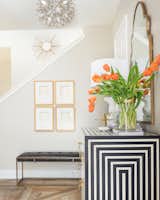 A boldly patterned black-and-white cabinet is the star of this stair hall and entryway, which has accents of rich golds that shine against a neutral taupe wall. Sculptural light fixtures also help give the space a sense of personality and richness.