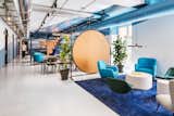Exposed ductwork gives the interiors an industrial edge, while colorful painted geometric forms add a lively, dynamic look. Plush seating in bright blues and greens keeps the space feeling fun and youthful.