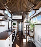 The interior reveals a well-lit, warm, and cozy space that is largely dominated by the full-size kitchen, although there is still space for a full bath in the back and a full-sized sofa that can open into to a guest bed.
