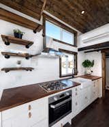 The kitchen has a propane cooktop and oven, ventilated by a stainless steel hood above. A clerestory window and another strategically located in front of the sink keep the kitchen well lit.