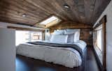 The lofted main sleeping area remains brightly lit and open to the outdoors with its skylight and clerestory windows on either side, offsetting the dark wood finish of the ceiling cladding.