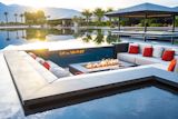 This poolside conversation pit is oriented around a fire pit at a vacation home in Coachella, California.