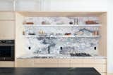 Breccia Capraia marble continues from the countertop to form the backsplash and open shelving.