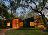 Austin-based architecture firm Thoughtbarn set out to renovate an H-shaped residence in a wooded, hilly neighborhood known for its midcentury, ranch-style homes, but quickly discovered that the home’s slab was structurally failing and would need to be replaced. This replacement ultimately led to the construction of a new home based on the footprint of the original—but with a small addition to the south. The exterior is clad in board-and-batten siding, while the front porch is covered with stained pine. Both materials have a vertical emphasis, which speaks to the heritage oak trees on the .75-acre property.