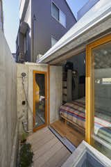 The bedroom opens out onto a small rear deck with potted plants and an outdoor shower.
