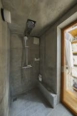 Bath Room, Open Shower, Ceramic Tile Floor, and Wall Lighting The concrete walls of the rest of the home continue into the shower room, where tile floors provide a different scale but similar color palette.  Photo 10 of 12 in A Concrete Tiny House in Tokyo Opens to the Sky—and the Street
