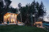 The deck near the home and the porch surrounding the house are lit up at night to allow for entertaining and outdoor living.