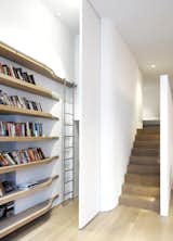 The stainless-steel ladder telescopes up and down and is a custom piece that travels along a curved track, imitating the form of the curved solid oak shelving. When pushed behind the sleeping loft to the laundry area, it is out of sight.
