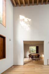 The interior material palette is even more subdued than the exterior, allowing the greenery of the forest to contrast with the simple white and wood finishes.