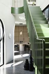 Kennedy Nolan selected a moody green color for the bent steel staircase with vertical bars. The staircase leads to a master suite on the upper level and adds a pop of color to the space.