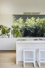 Both windows and doors in the kitchen provide views of greenery. The kitchen island features the stone that inspired the color palette for the rest of the home's interior.