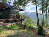 Nestled in the hills of the Smoky Mountains and oriented to prioritize views of the Appalachian Trail, this prefab cabin in North Carolina is constructed out of three shipping containers topped with a double-sided overhang that creates two porches. The upper-level shipping container is available to rent on Airbnb.