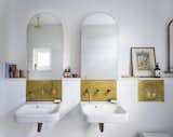 Vault House by Studio Ben Allen bathrooms with arched mirrors and uncoated brass fixtures
