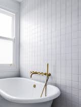 The bath fixtures received a similar treatment of uncoated brass that gleams against a backdrop of white tile.