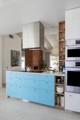 Kitchen, Range Hood, Wall Oven, Colorful Cabinet, and White Cabinet Mahle also enlarged the opening to the dining room, enabling better sight lines and daylight to pass through the space.  Photos from Budget Breakdown: An Interior Designer Livens Up Her Dated Kitchen for $57K