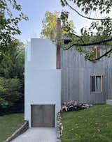 The original home was reclad in reclaimed barn wood laid up vertically; the new addition in white stucco was separated by a gap that formed a skylight on the interior.