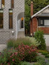 The entry steps, made of concrete, are bordered by a minimalist white picket fence with wood handrails. Even the pickets reiterate the curves of the entry area.