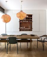 The dining room, with its minimalist furniture and white cabinetry with hidden hardware, features a "secret