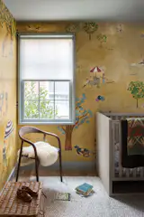 A playful wallpaper mural with a mustard-yellow background line the walls of their daughter's room.