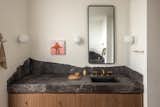 The asymmetrical vanities on opposite walls in the primary bathroom feature stone tops and backsplashes with a chiseled free edge -- a detail that came together from the collaboration between Fowlkes Studio and their clients. The free edges were designed to evoke broken stone and be different from each other, the edges reflect in the opposing mirrors.