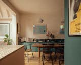 The cabinetry, made from softer-patterned plywood stained with pink linseed oil, is topped by terrazzo and stainless steel countertops. The dining area has similar cabinetry, stained green.