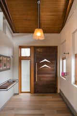 The front door was created with recycled wood beams from the original home, accented with the same boomerang cut-outs from exterior copper canopy. To maximize open floor space, Curtis Micklish designed this floating shelf to catch keys and mail and the occasional tiny toy. 
