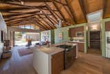 Overhead trusses made from recycled wood beams from the original home support a dramatic 16 foot ceiling. To keep the line of site wide open, an overhead hood was swapped out for a Jenn-air downdraft gas range.