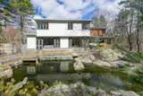 The south elevation of the original house overlooks a koi pond and the wooded landscape.  The new addition continues its massing, but uses clear-finished siding milled from reclaimed lumber to contrast with the smooth, painted finish of the historic house.
