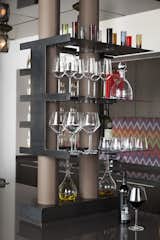 Custom steel shelves hold barware, and handstitched leather conceals pipes.