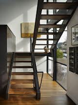 The stair, with its solid walnut treads and black wide-flange stringers, screens the main living areas from the street. The perforated steel fireplace mass serves as a guardrail as well as a screen.