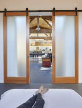 The bedroom is tucked behind Douglas fir and glass barn doors. 