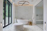 The master bath boasts a stand-alone tub that sits against a bespoke cherry blossom mosaic wall, glass enclosed steam shower, dual vanities, and adjacent his and hers closets.