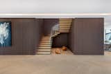 A floating wood-glass staircase surrounded by wood panels leads to the upstairs.